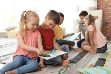 Cute little children reading book together indoors. Learning by playing