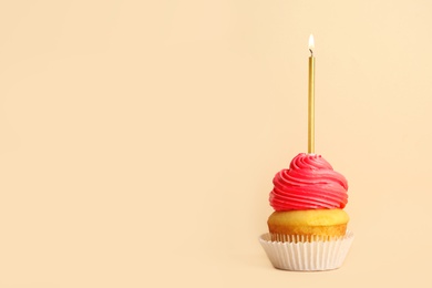 Photo of Birthday cupcake with candle on beige background, space for text