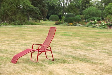 Photo of Red deck chair on green grass in park. Space for text