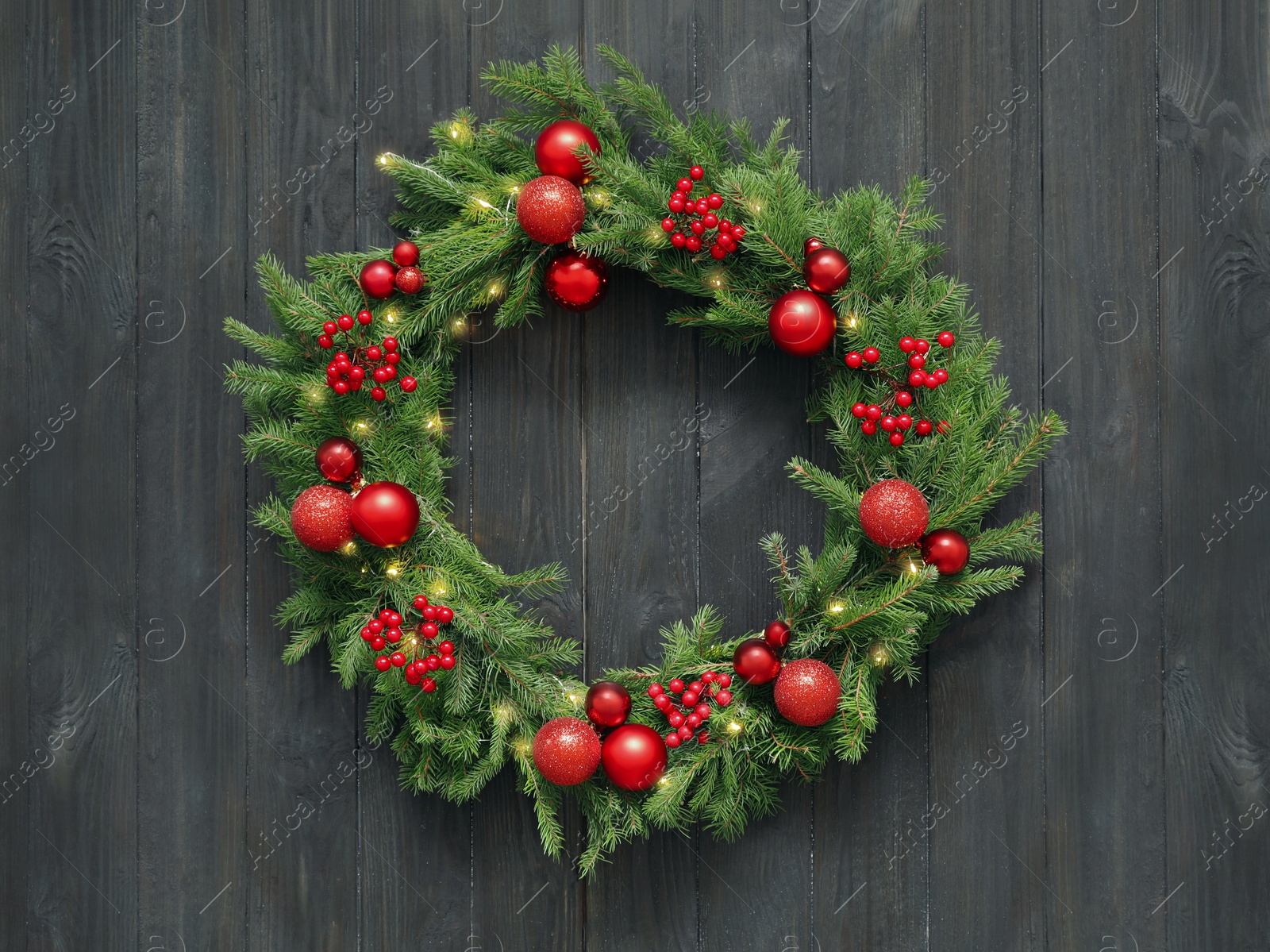 Photo of Beautiful Christmas wreath with festive decor on black wooden background, top view