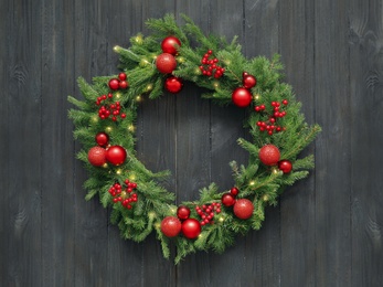 Photo of Beautiful Christmas wreath with festive decor on black wooden background, top view