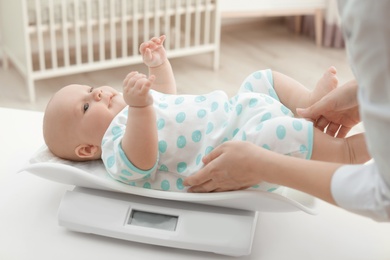 Doctor weighting baby on scales in light room