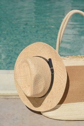 Photo of Stylish bag and hat near outdoor swimming pool on sunny day. Beach accessories