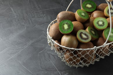 Photo of Fresh ripe kiwis in metal basket on grey table, space for text