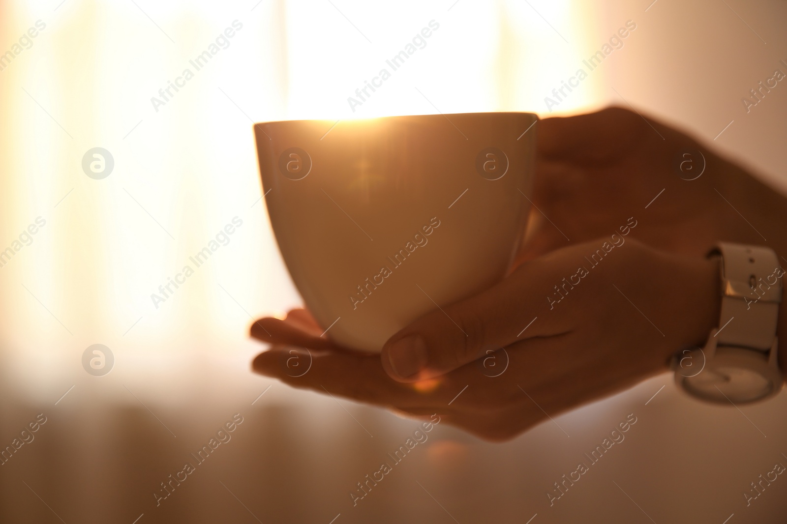 Photo of Woman holding cup of drink on blurred background, closeup. Lazy morning