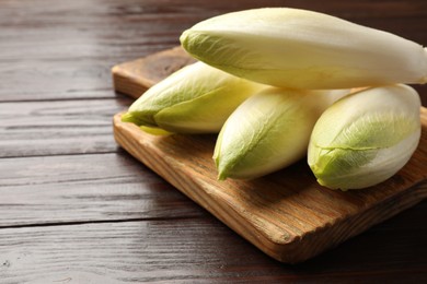 Photo of Raw ripe chicories on wooden table, closeup. Space for text