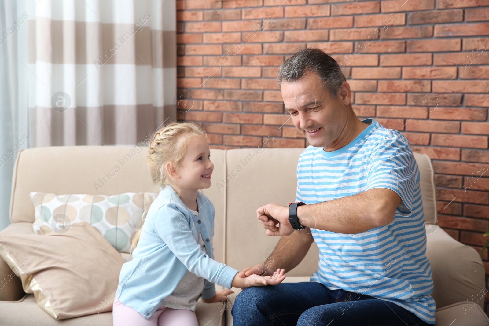 Photo of Mature man checking little girl's pulse with fingers at home