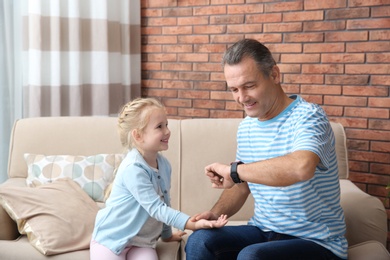 Mature man checking little girl's pulse with fingers at home