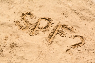 Photo of Abbreviation SPF and question mark written on sand at beach, above view