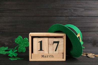 Leprechaun's hat, block calendar and St. Patrick's day decor on black wooden table