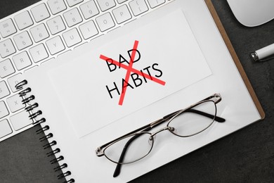 Break bad habits. Text crossed with red lines in notebook, eyeglasses and computer keyboard on black table, flat lay