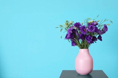 Photo of Beautiful bouquet of purple eustoma flowers in vase and space for text on color background