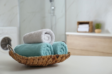Photo of Wicker tray with clean soft towels in bathroom. Space for text