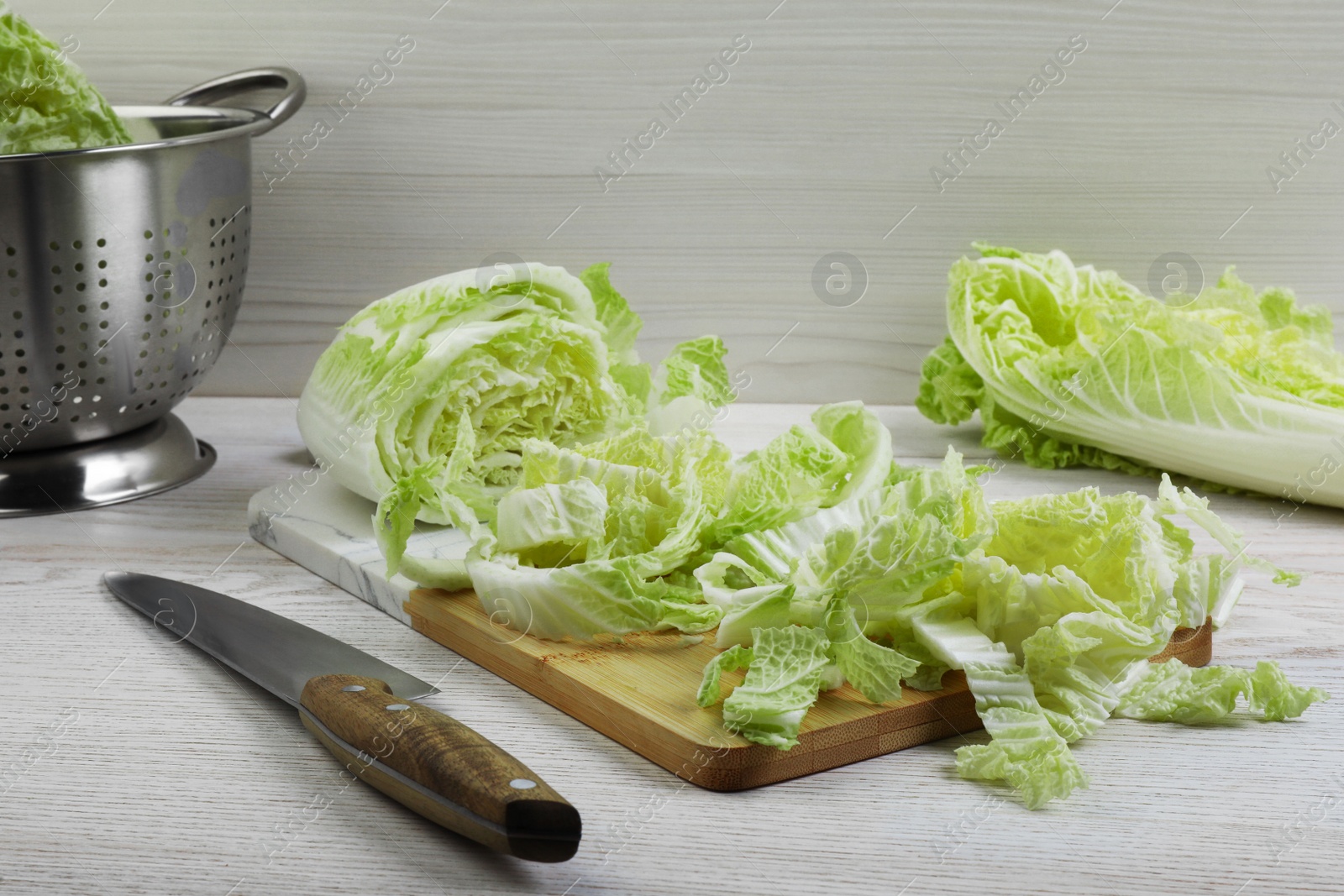 Photo of Chopped Chinese cabbage and knife on white wooden kitchen table