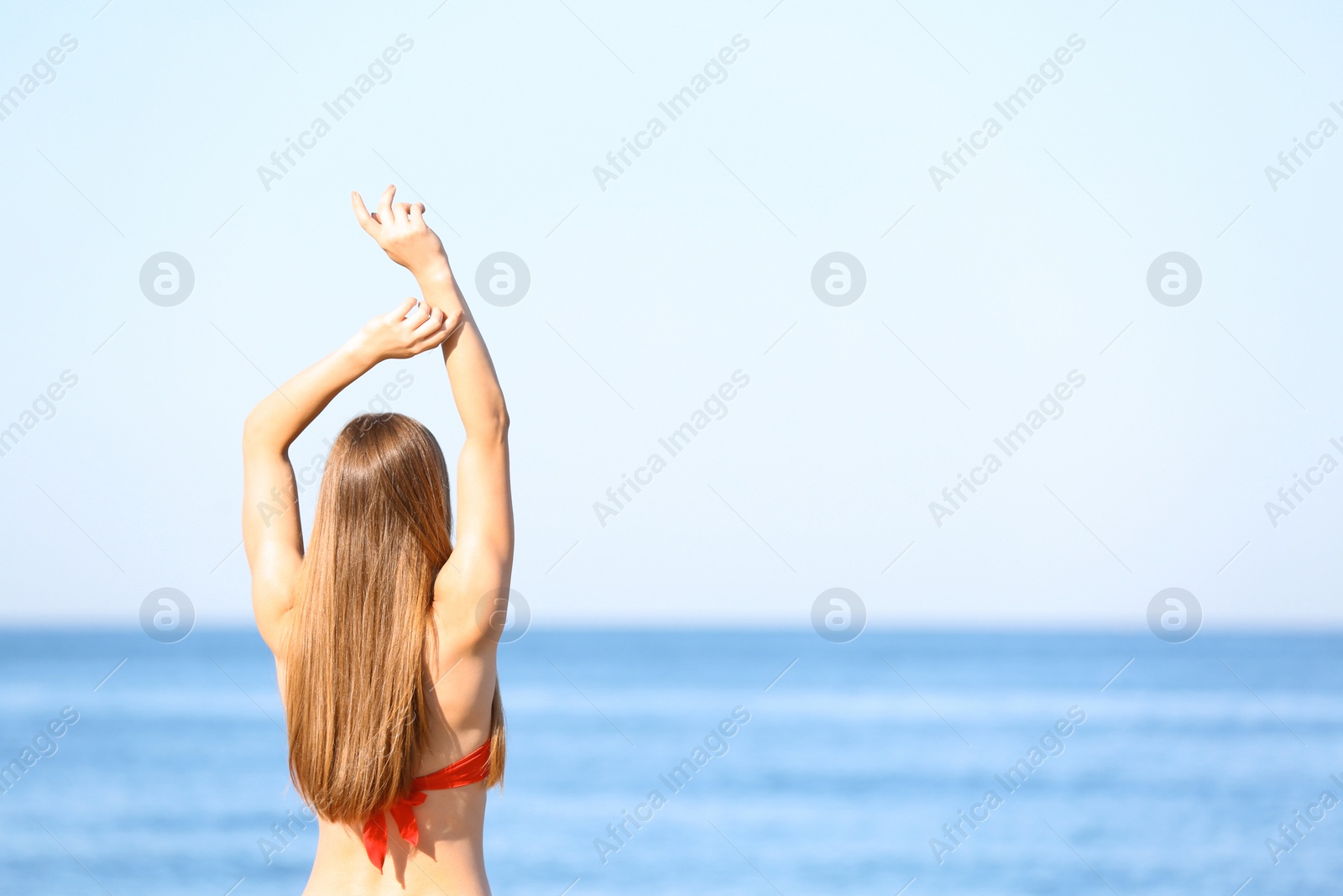 Photo of Young woman in red bikini near sea. Space for text