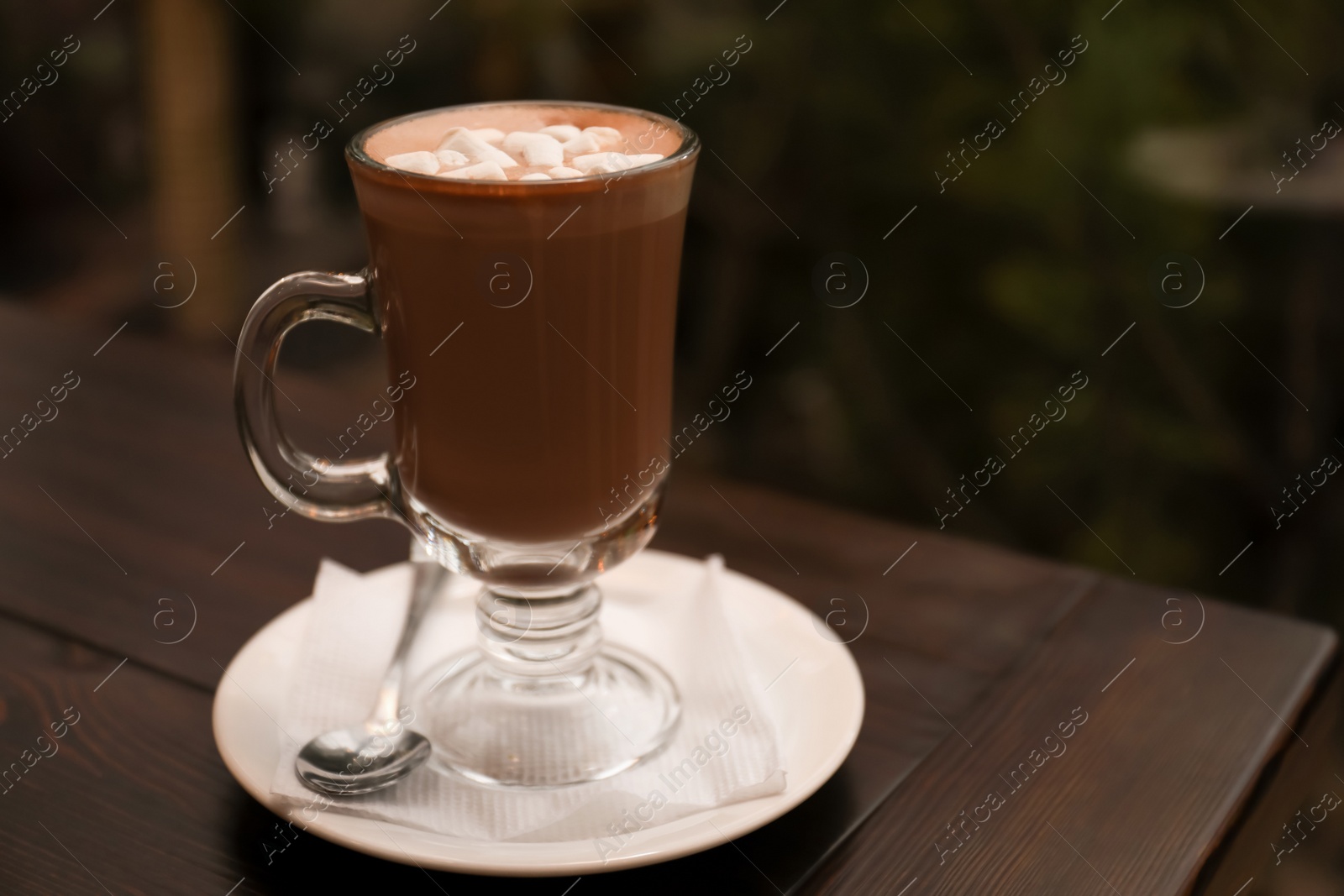 Photo of Cup of aromatic cacao on table against blurred background. Space for text