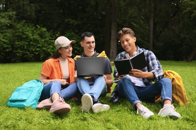 Photo of Happy young students learning together on green grass in park