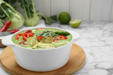 Photo of Saucepan with delicious green curry chicken soup on white marble table