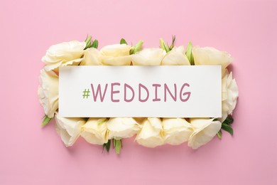 Beautiful Eustoma flowers and card with hashtag Wedding on pink background, flat lay