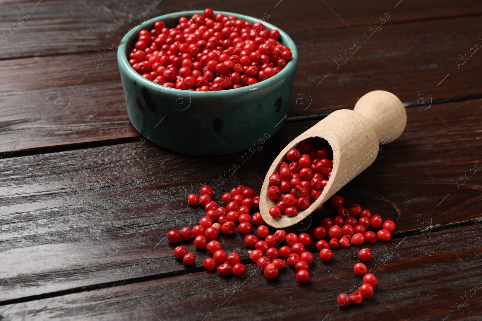 Photo of Aromatic spice. Red pepper in bowl and scoop on wooden table, closeup