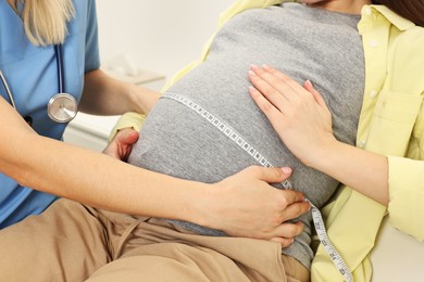 Photo of Pregnancy checkup. Doctor measuring patient's tummy in clinic, closeup