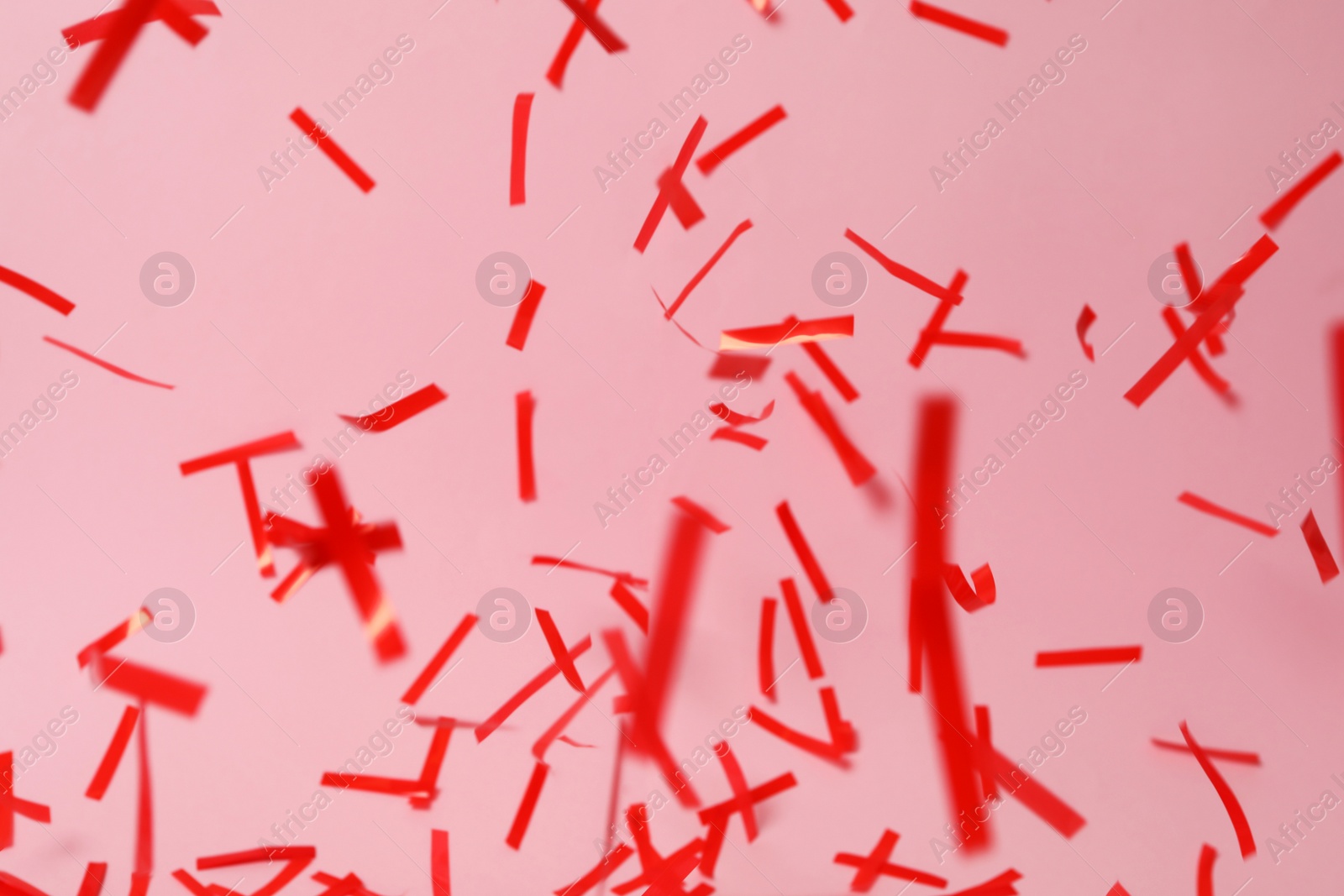 Photo of Shiny red confetti falling down on pink background