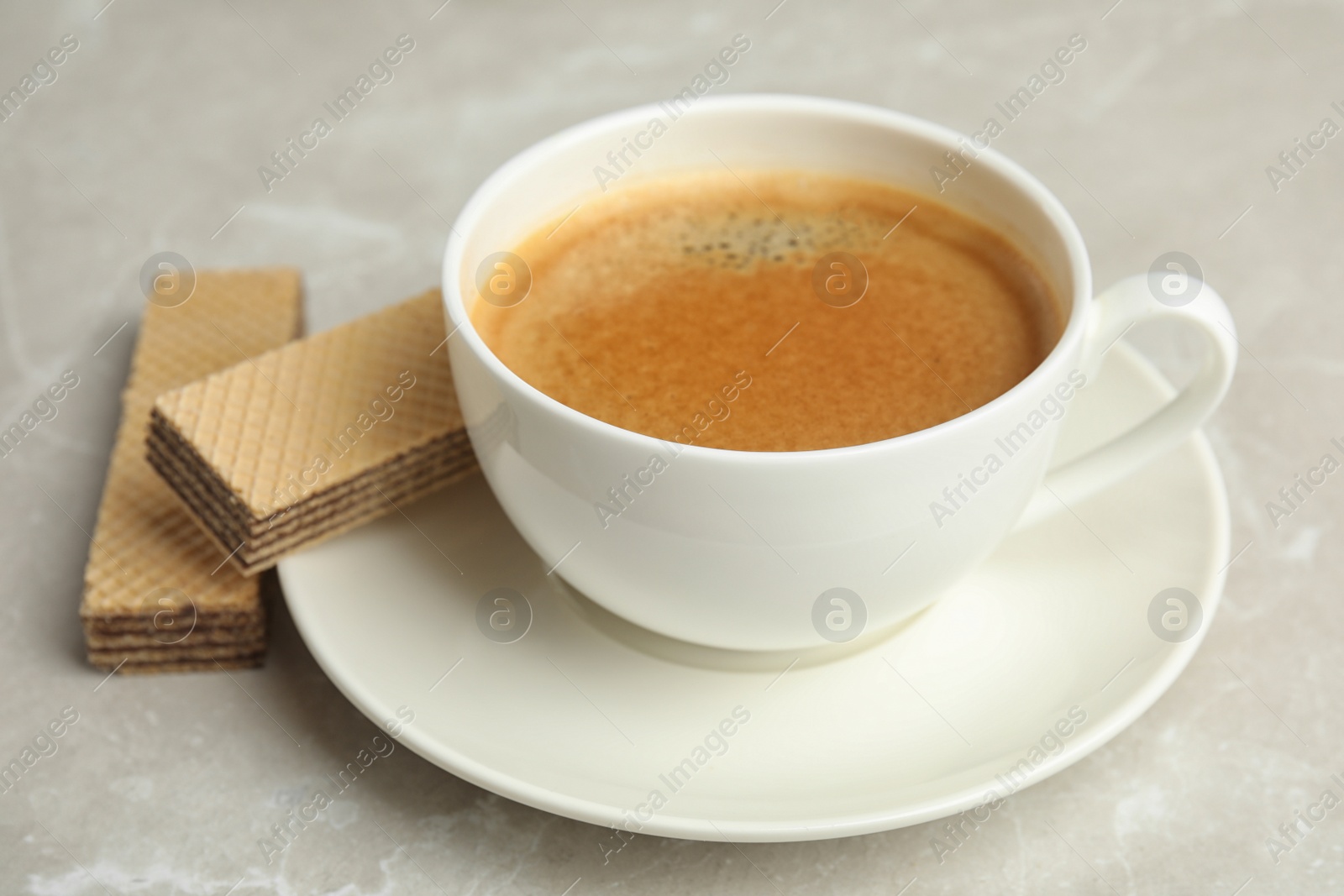 Photo of Delicious wafers and cup of coffee for breakfast on grey marble table