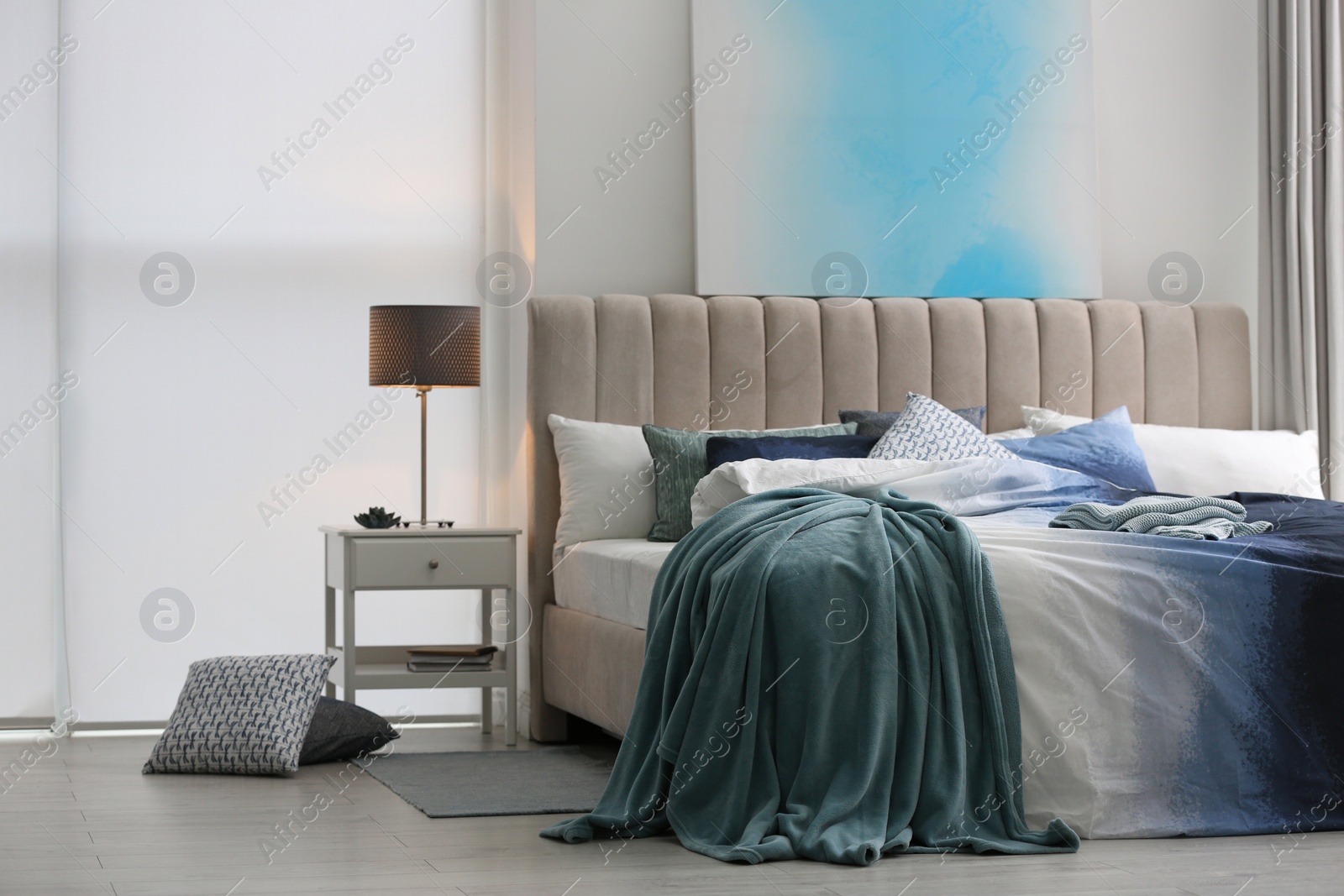 Photo of Comfortable bed with pillows and soft blanket in room. Stylish interior design