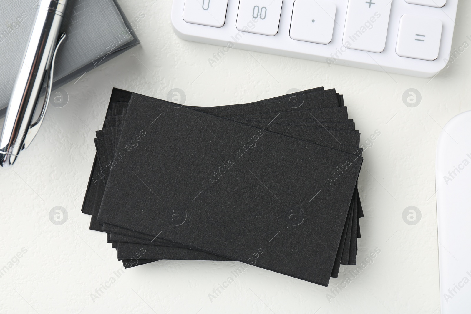 Photo of Blank black business cards, calculator, pen and notebook on white table, flat lay. Mockup for design