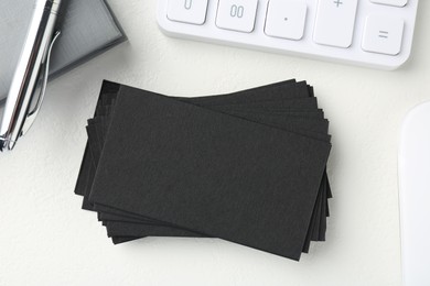 Blank black business cards, calculator, pen and notebook on white table, flat lay. Mockup for design