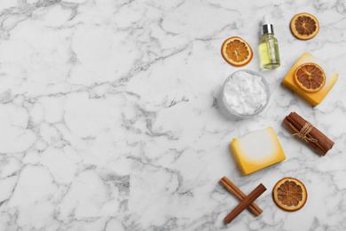 Flat lay composition with natural handmade soap and ingredients on white marble table, space for text