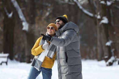 Photo of Happy young couple walking in snowy park on winter day