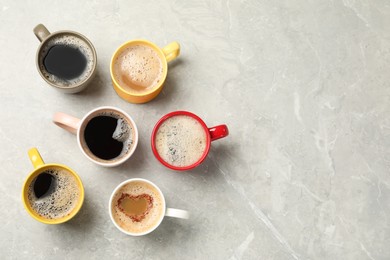 Many cups with different aromatic coffee on light grey marble table, flat lay. Space for text