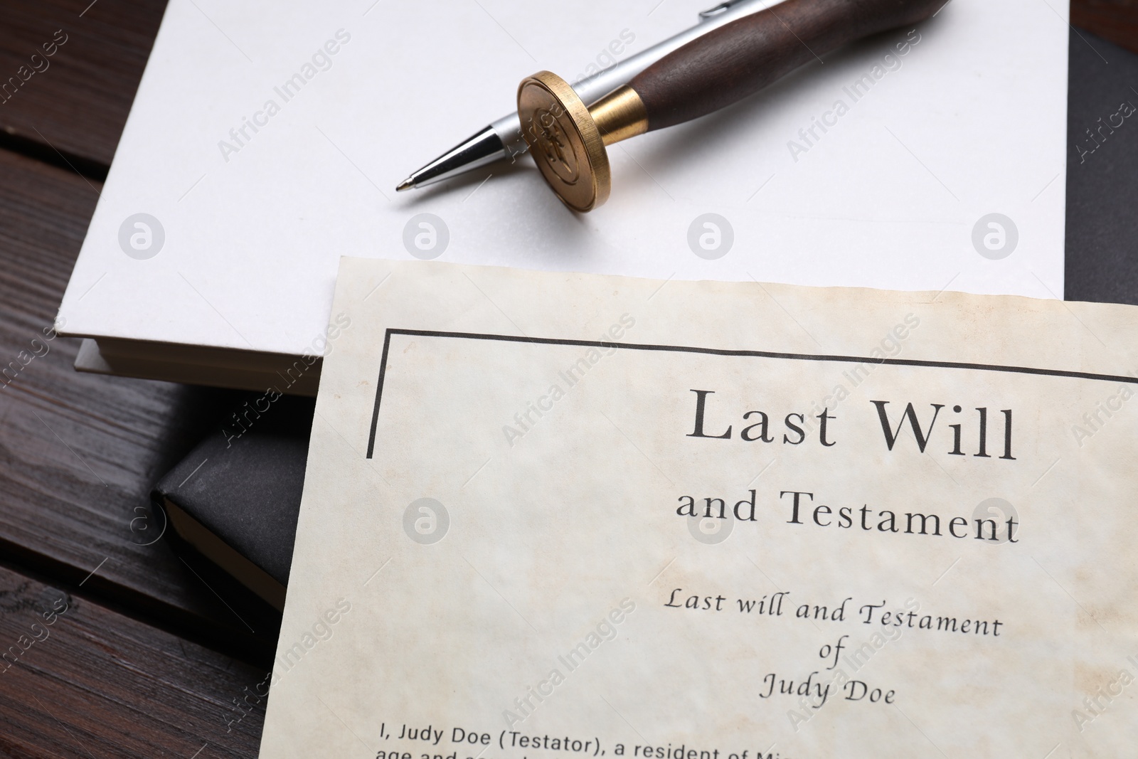 Photo of Last Will and Testament, books, stamp seal and pen on wooden table, closeup