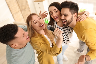 Happy friends singing karaoke together at home