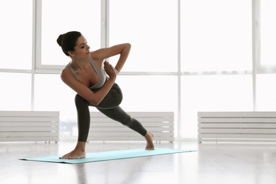 Young woman practicing revolved crescent lunge asana in yoga studio. Parivrtta Anjaneyasana pose