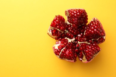 Photo of Cut fresh pomegranate on yellow background, top view. Space for text