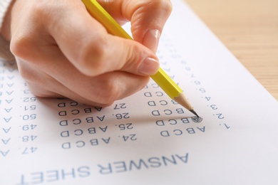 Photo of Student filling answer sheet at table, closeup