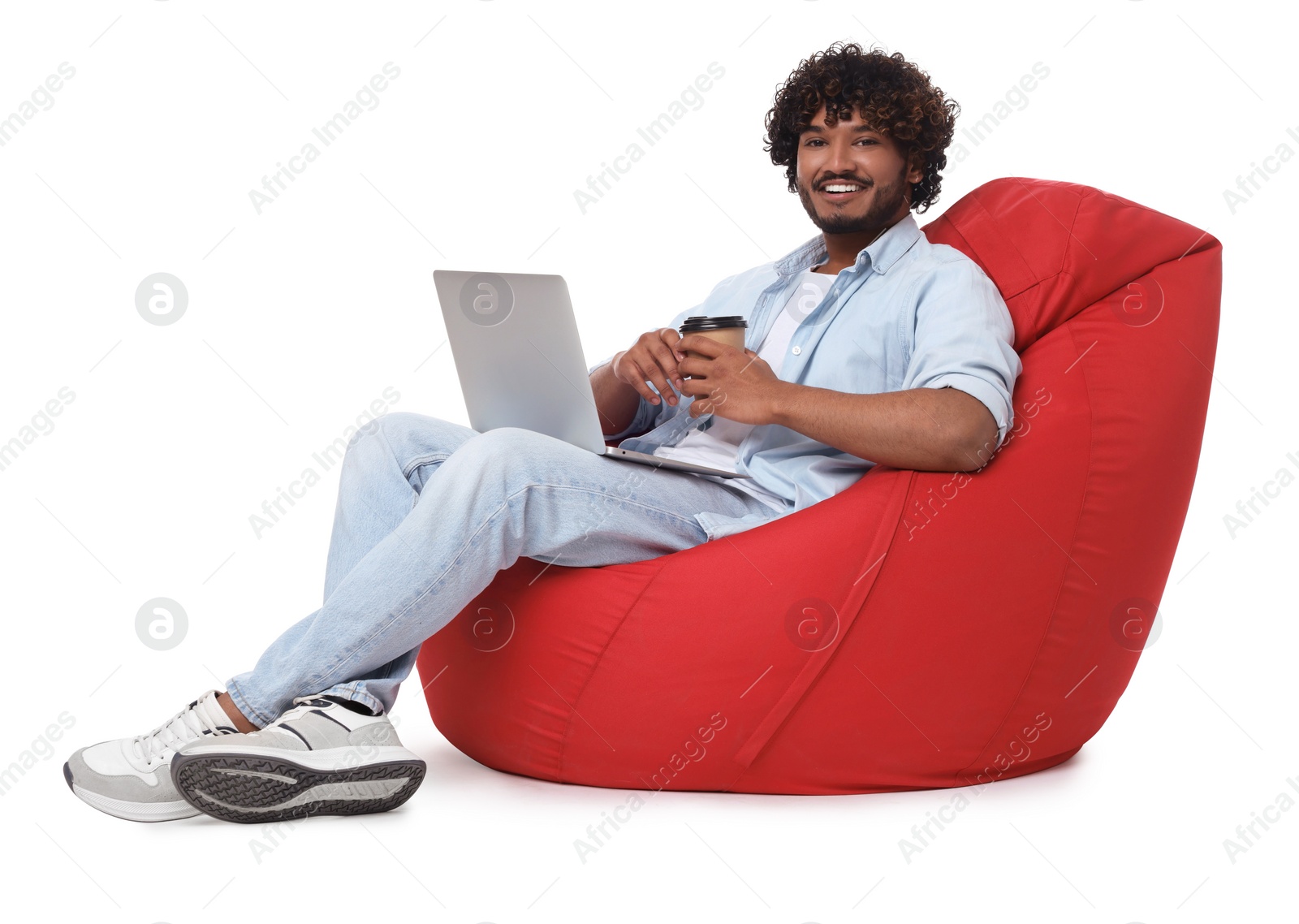 Photo of Smiling man with laptop sitting on beanbag chair against white background