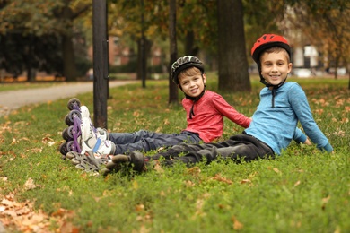 Photo of Cute roller skaters sitting on grass in park