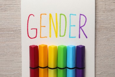 Photo of Notebook with word Gender and felt tip pens on wooden table, top view