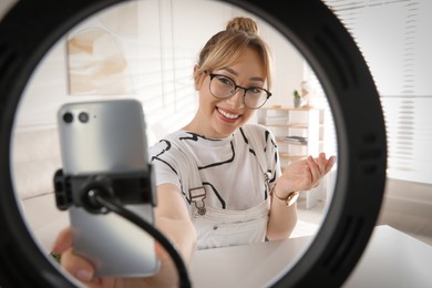 Photo of Blogger recording video at home, view through ring lamp