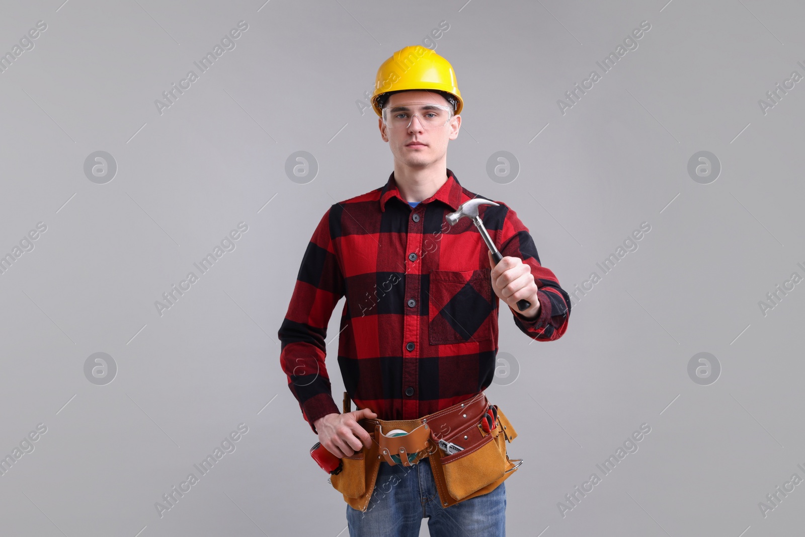 Photo of Professional repairman holding hammer on light grey background