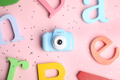 Photo of Toy camera and colorful wooden letters on pink background, flat lay. Future photographer