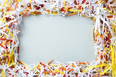 Frame of shredded colorful paper strips on white background, flat lay. Space for text