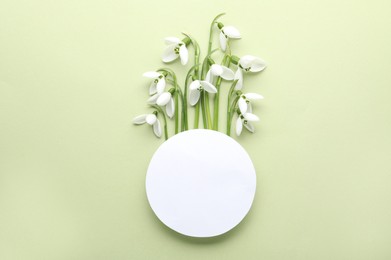 Photo of Beautiful snowdrops and paper card on light background, flat lay. Space for text