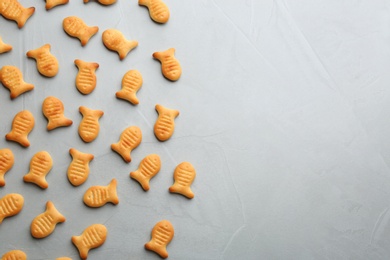 Delicious goldfish crackers on grey table, flat lay. Space for text