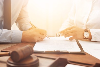 Image of Lawyer pointing at document and client putting signature at table in office, closeup