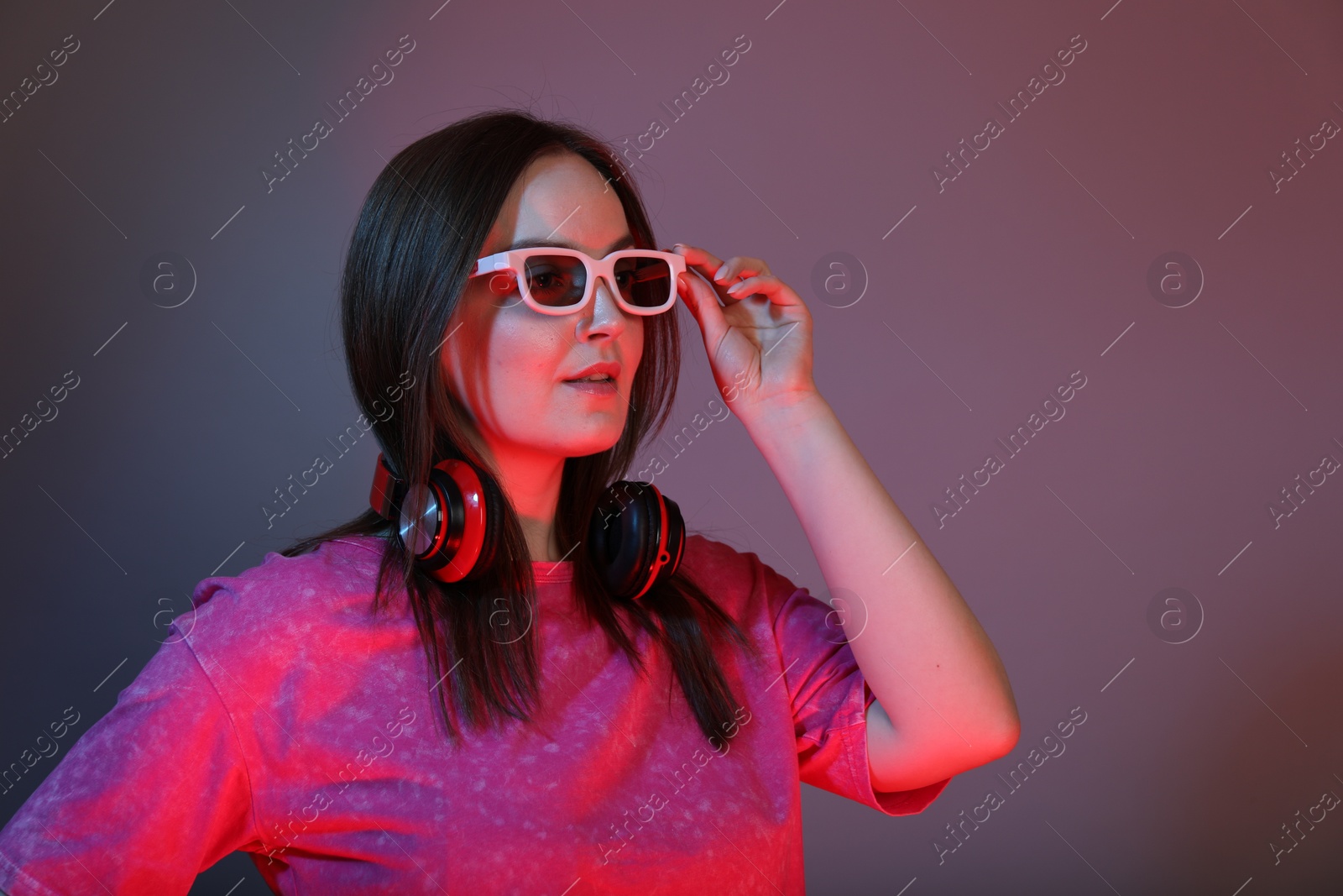 Photo of Stylish woman with headphones wearing sunglasses on color background, space for text