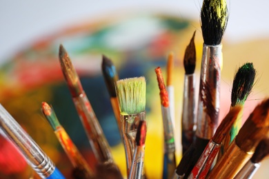 Different paint brushes on blurred background, closeup